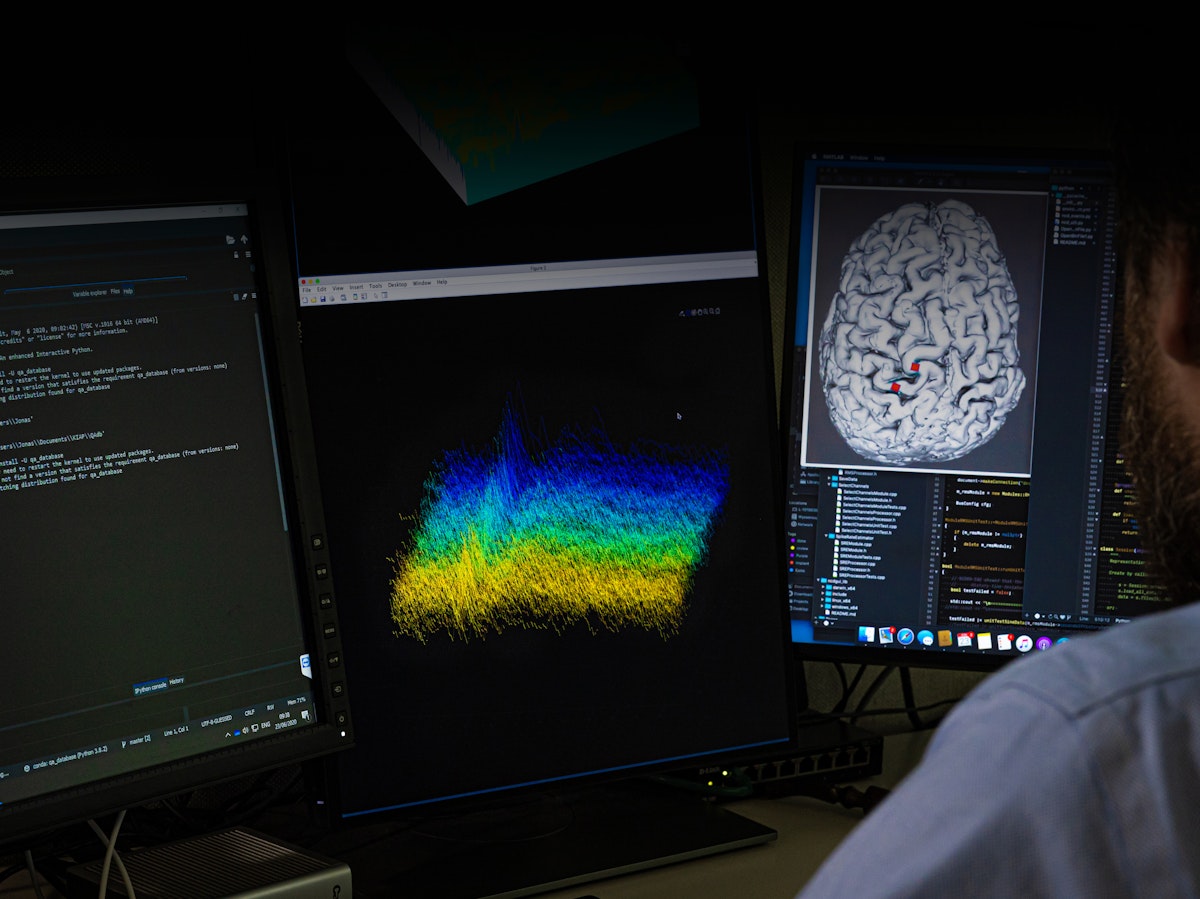 Wyss Center employee looks at brain and data on computer
